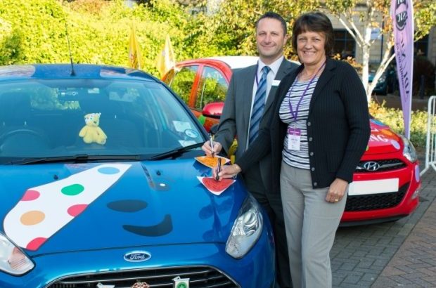 Lesley Young and Mark Magee signing a car for children in need