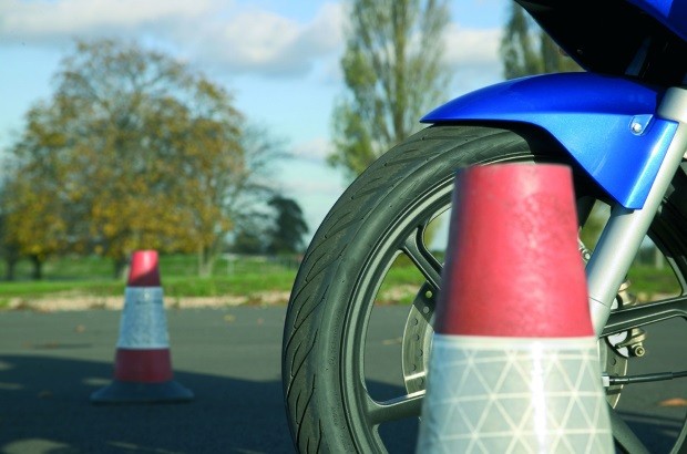 A blue motorcycle, between two orange cones, on a training circuit.