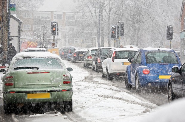 Cars driving in snow at a set of traffic lights