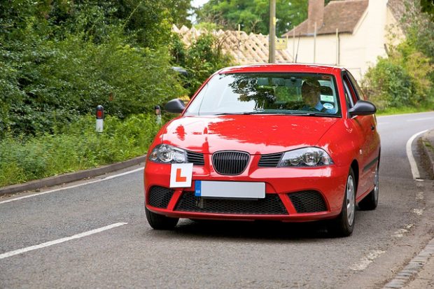 Learner driving red car down road