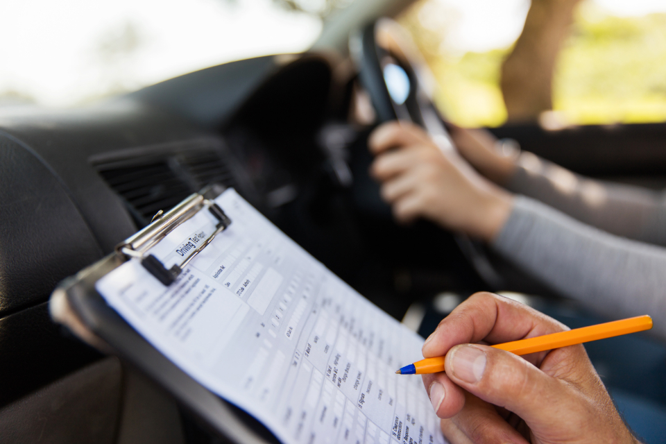 A driving instructor instructor filling in a mock driving test report form.