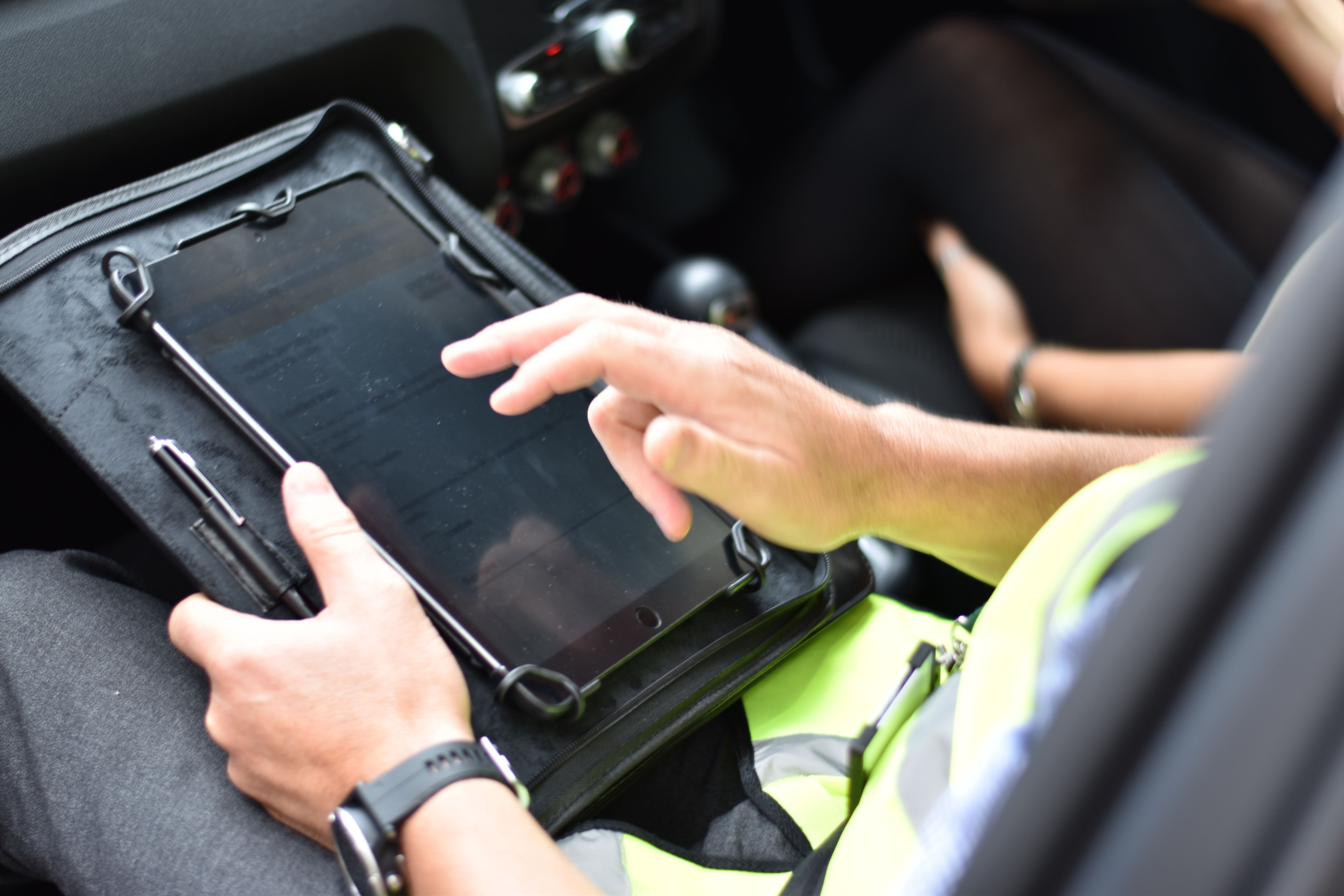 Close-up of an examiner holding a tablet inside a car