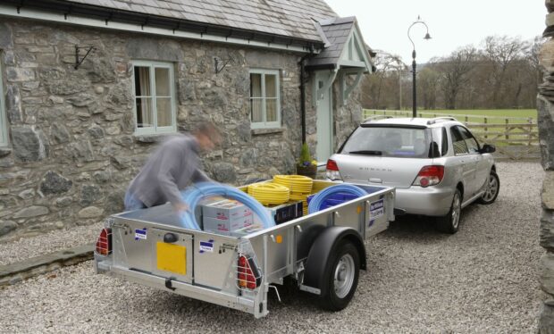 A car with trailer being loaded outside a cottage