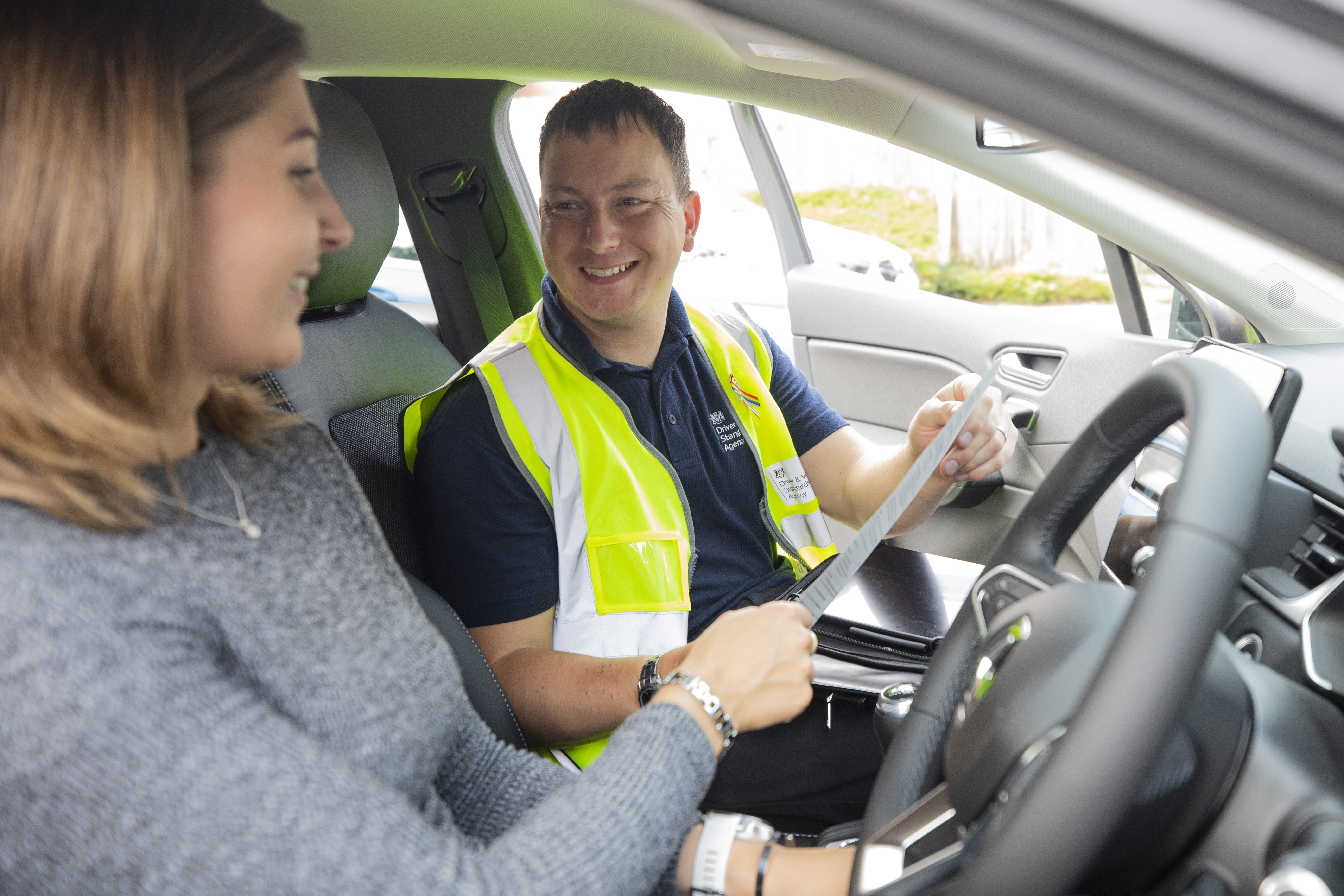 A driving examiner handing a test candidate their physical pass certificate
