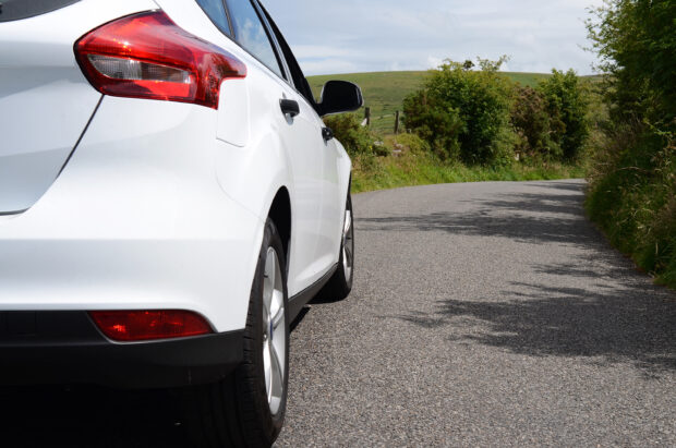 Close up of white car driving along a country road